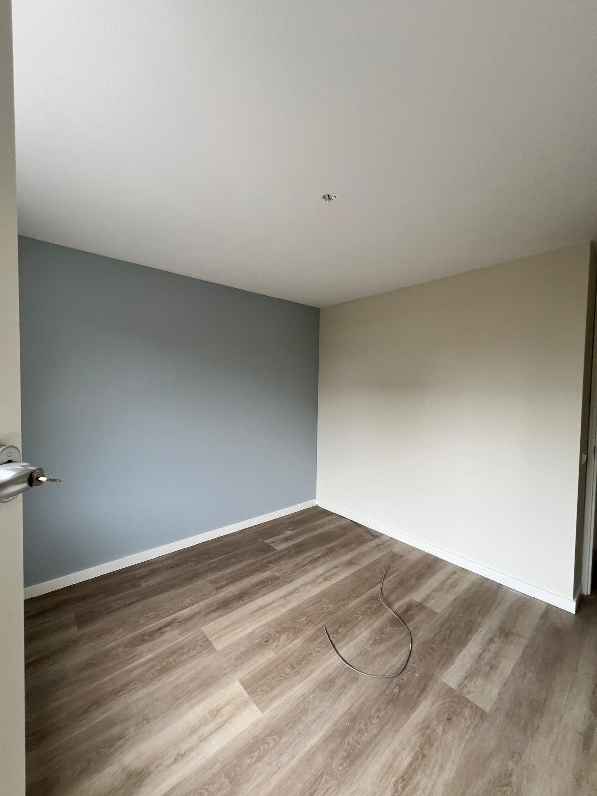 Slaapkamer met blauwe accentwand en witte plinten