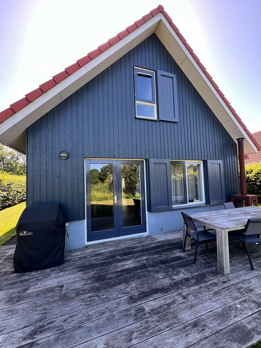 Geschilderde villa gevel met rode dakpannen en grijze kozijnen