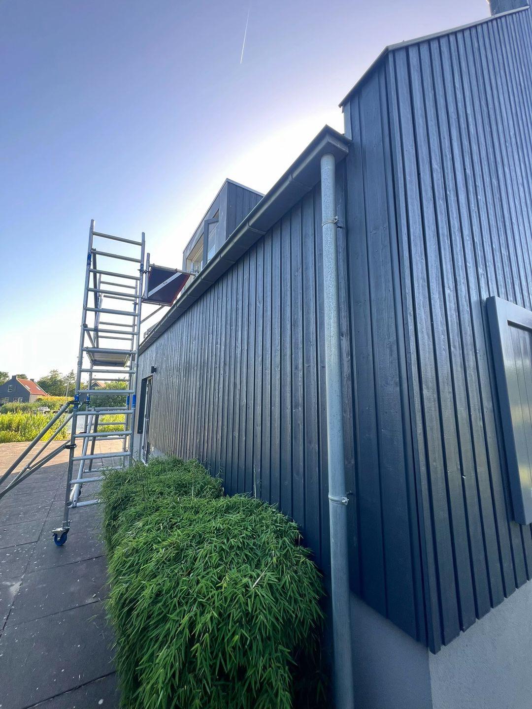 Gevelonderhoud met ladder langs geschilderd houtwerk