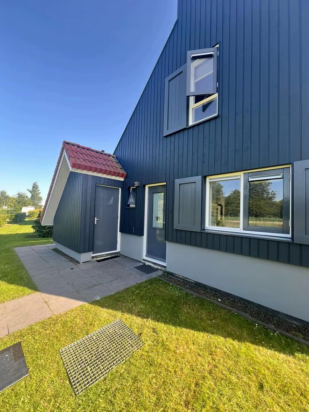 Voorgevel villa met grijze deur, luiken en rode dakrand