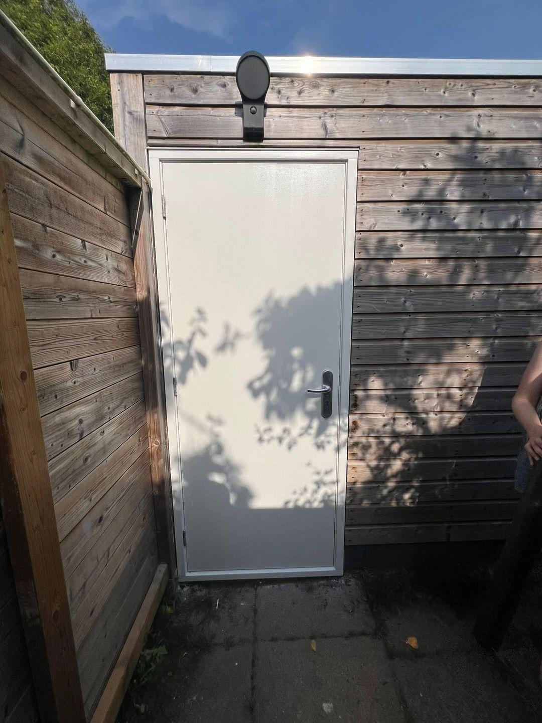 Geschilderde houten schuurdeur in tuin in Delft
