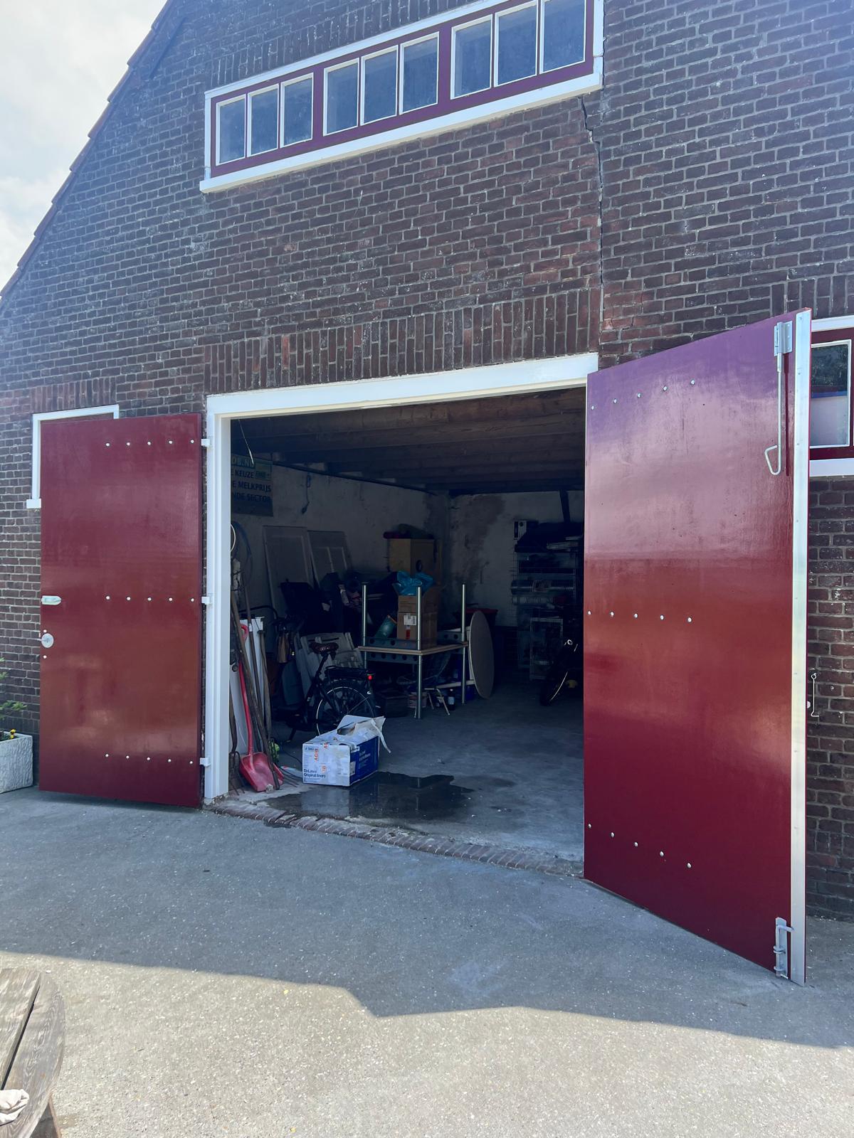 Grote rode schuurdeuren van de boerderij na het schilderwerk