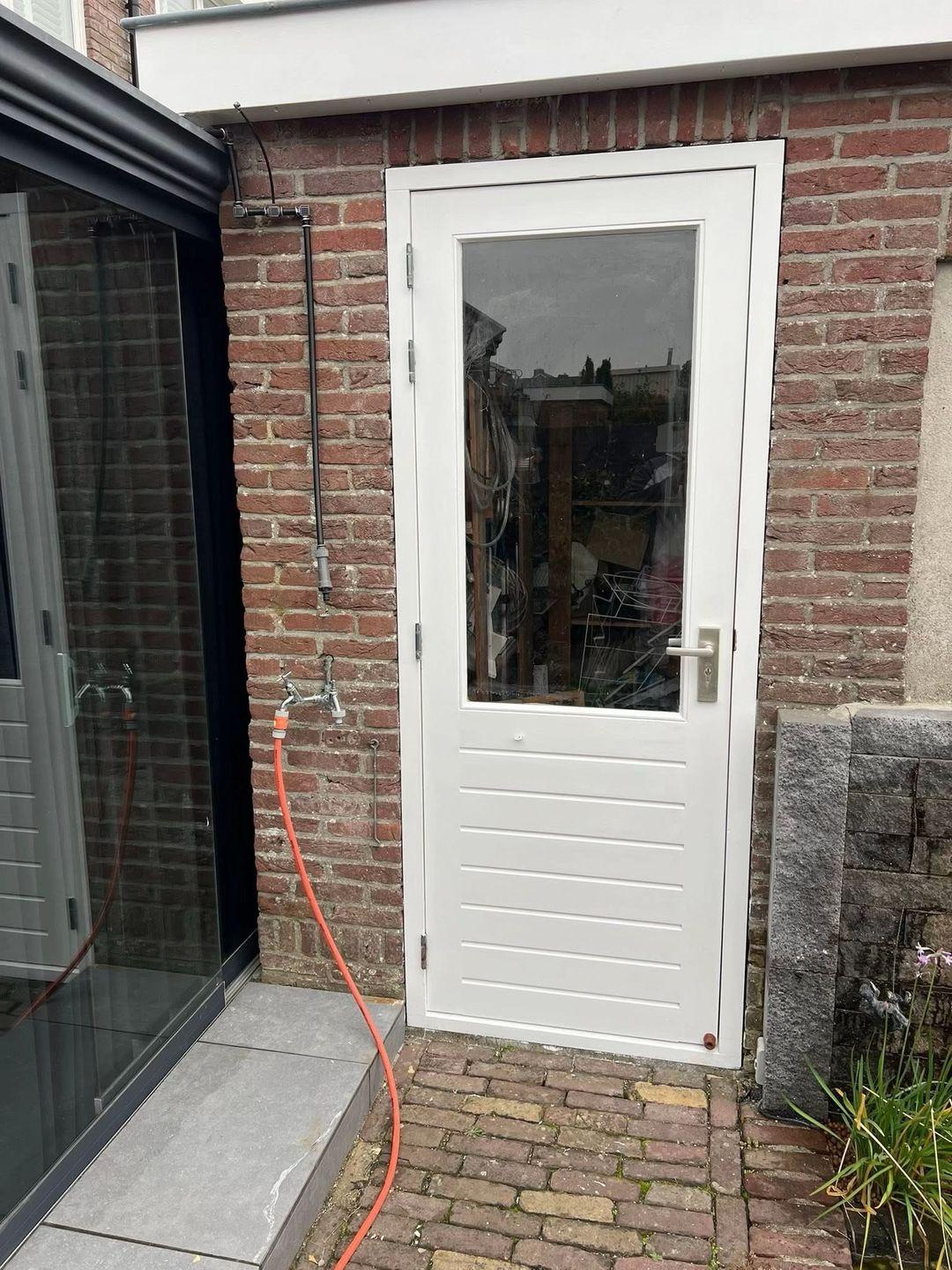 Detail van wit geschilderde achterdeur met kozijn in Sassenheim