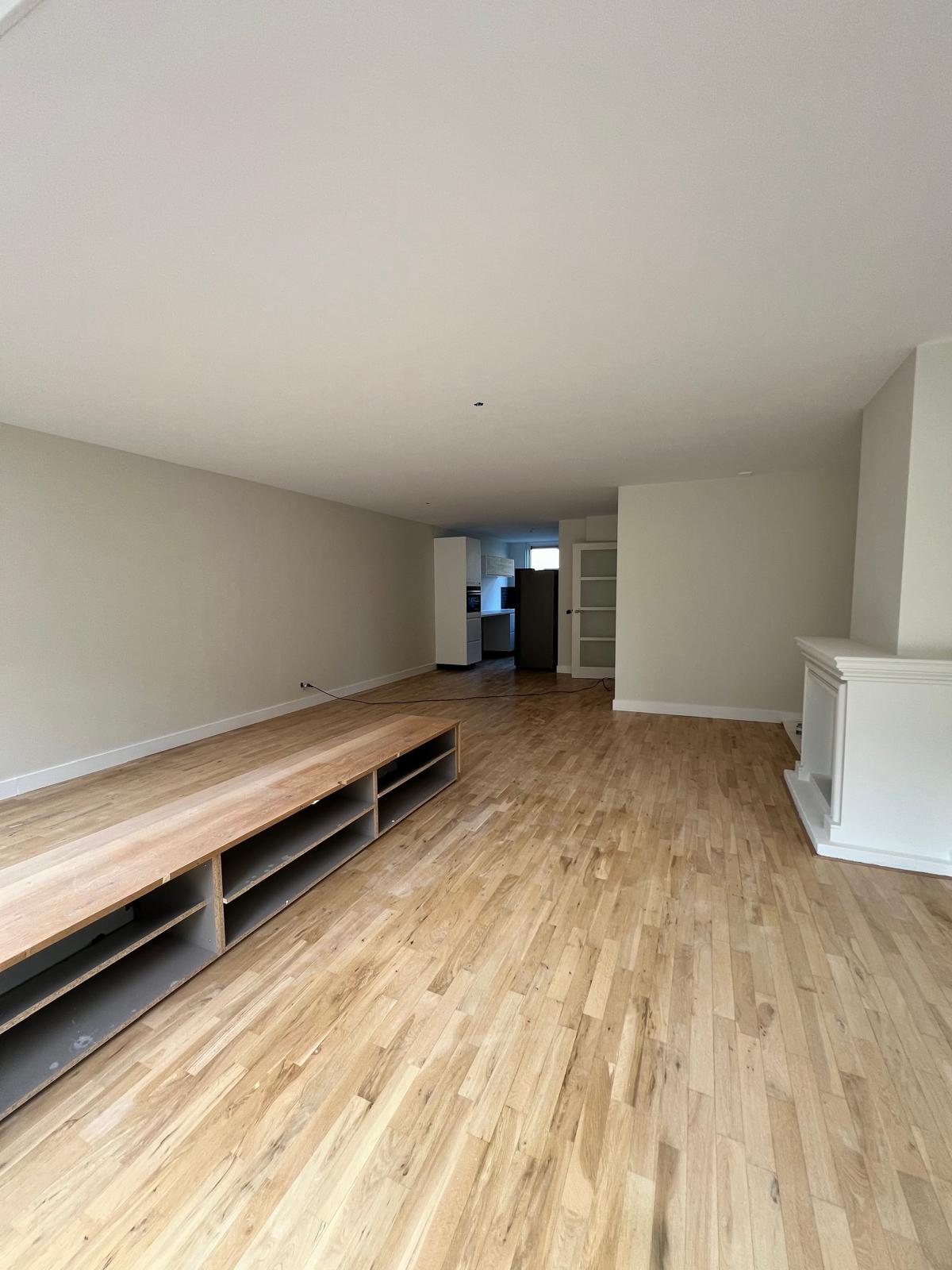 Woonkamer met houten vloer, TV-meubel en lichte wanden