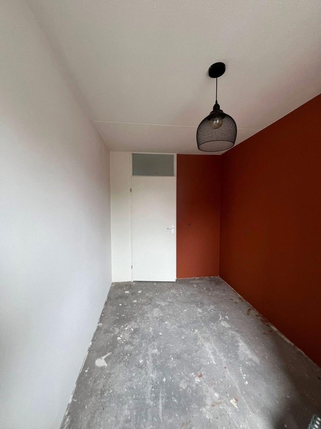 Kamer met witte deur en terracotta accentwand in Zoetermeer