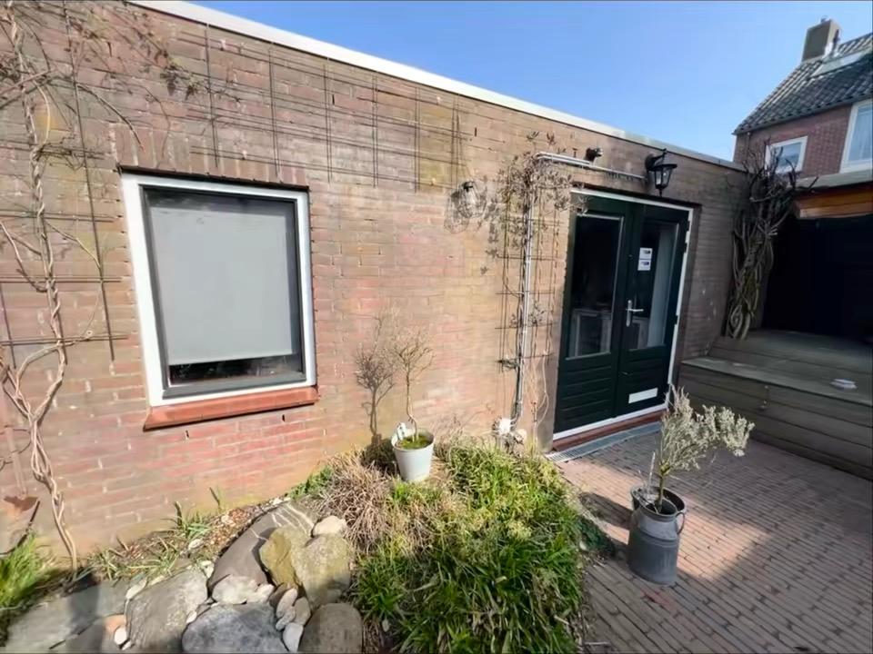 Zijgevel met groene voordeur en geschilderd raam in Rotterdam