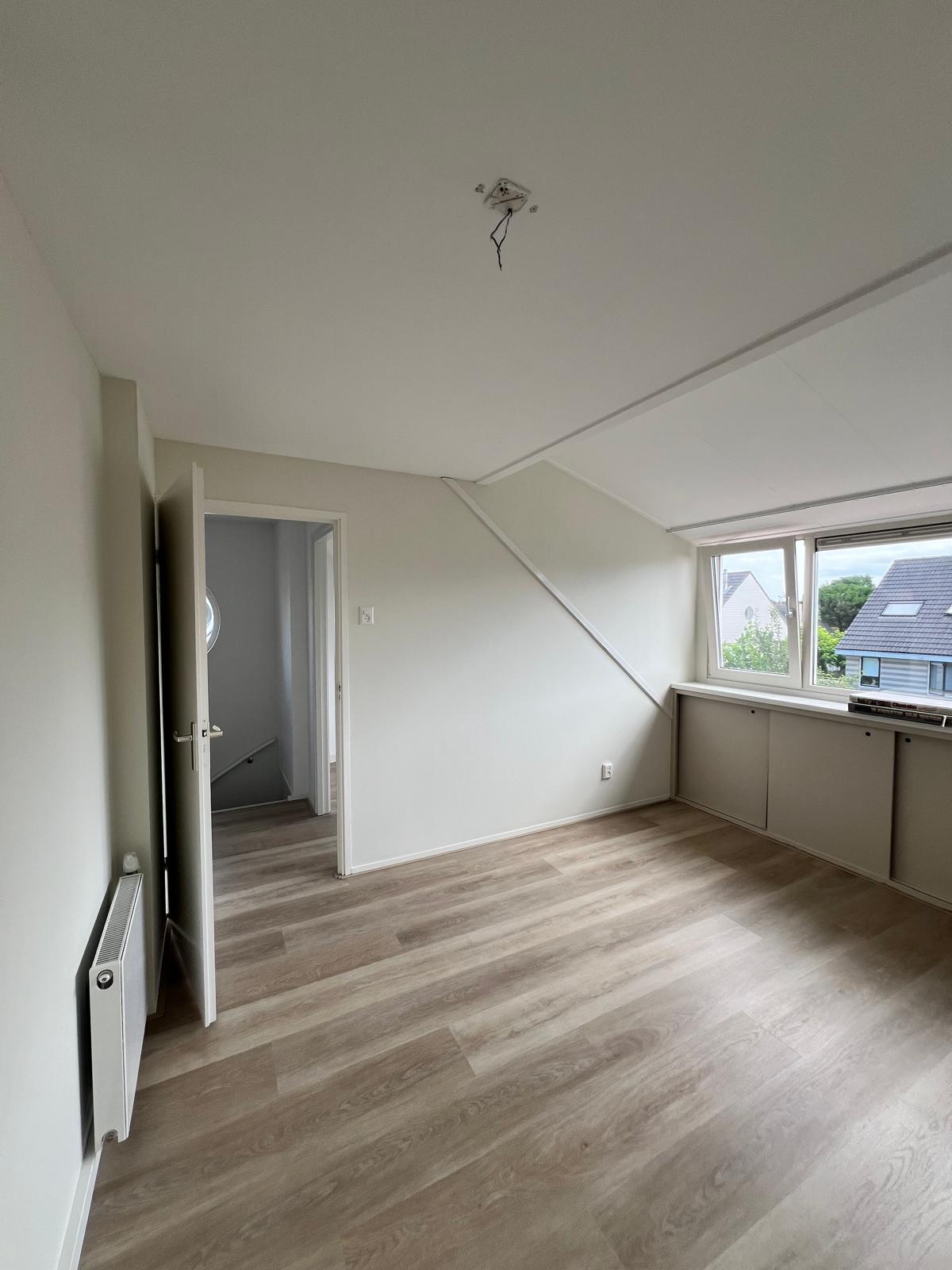 Zolderkamer met dakkapel en strak geschilderde wanden
