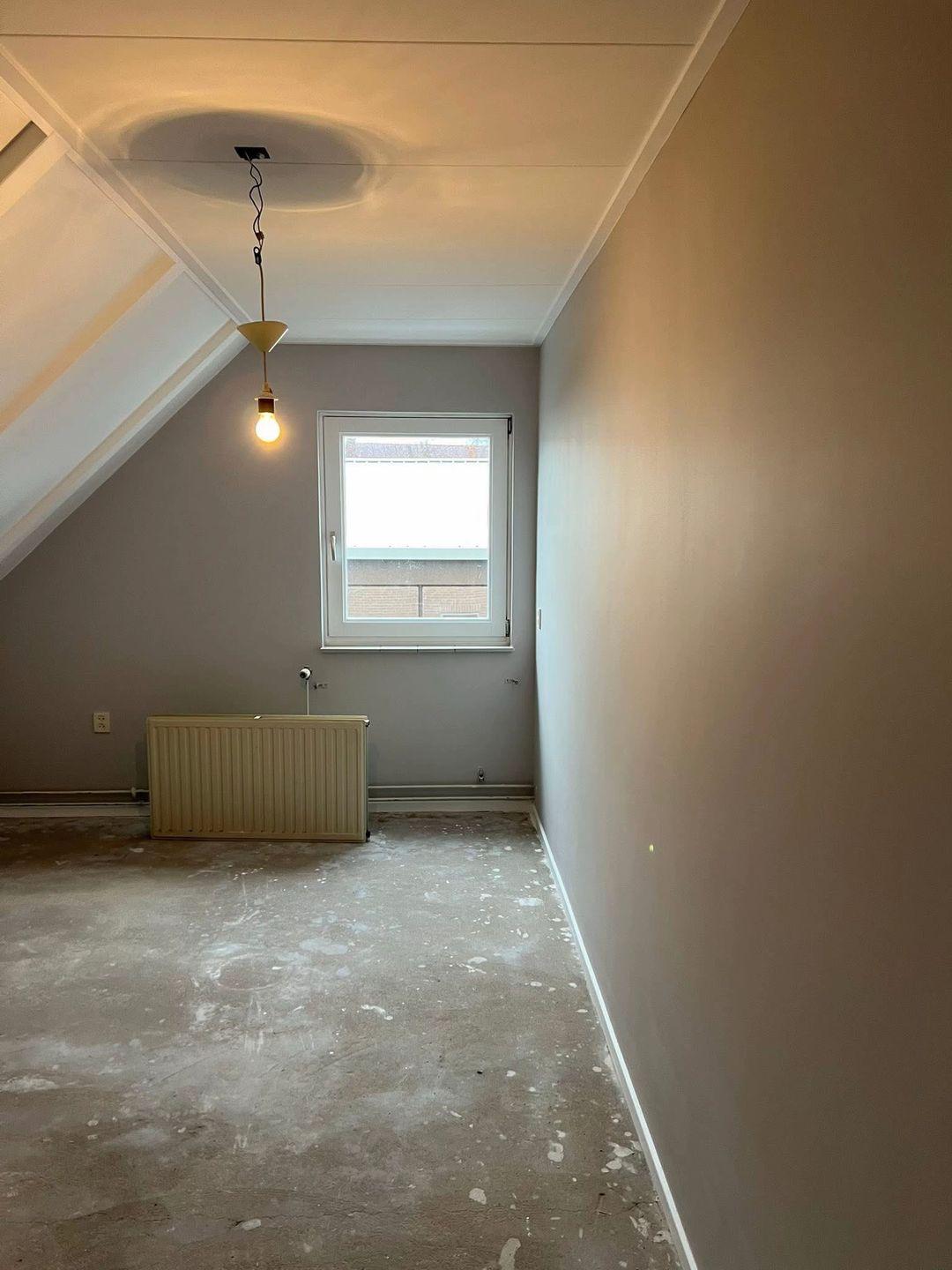 Kamer met geschilderde wanden, raam en radiator na voorbereiding
