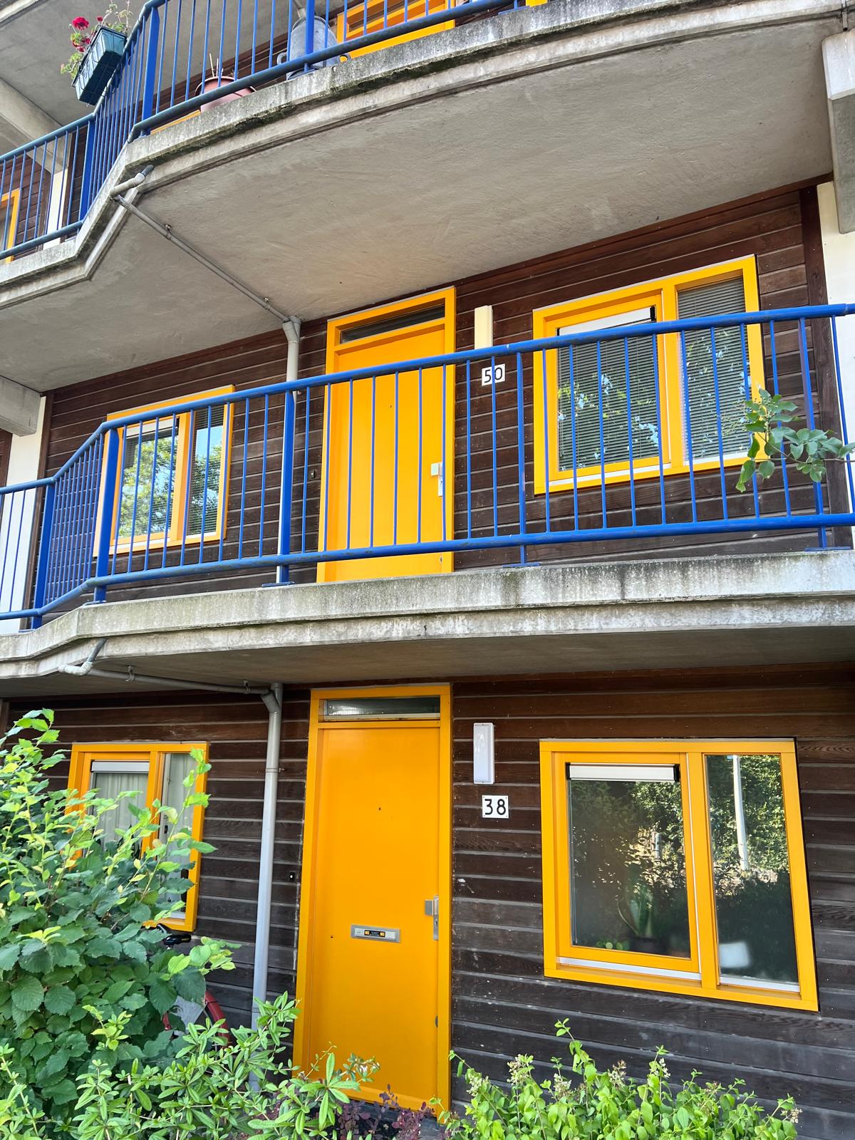 Geschilderde gele deuren en ramen op balkon van VvE complex