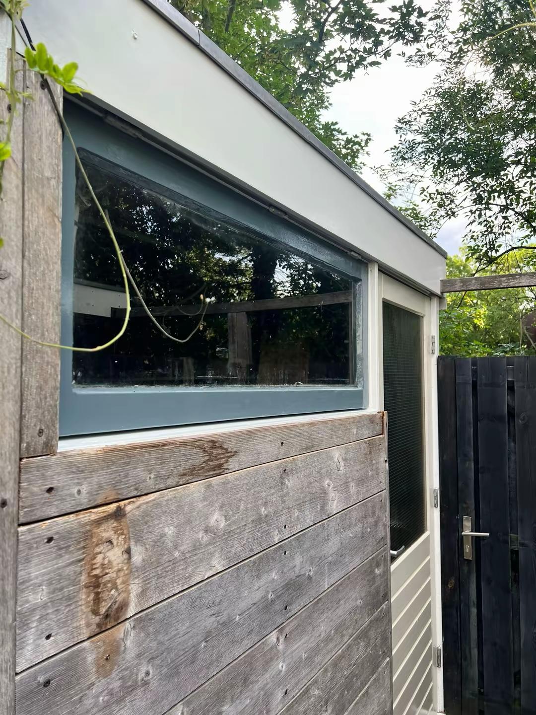 Houten schuur met gerepareerd houtrot en geschilderde raamkozijnen