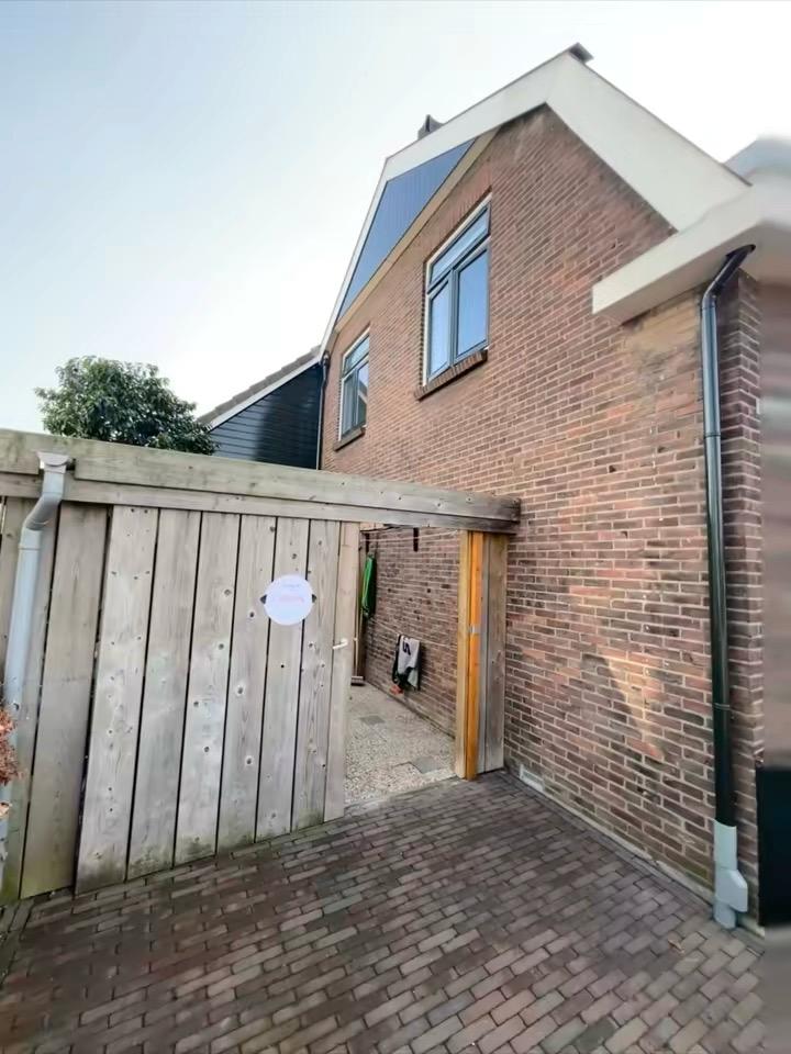 Zijgevel met geschilderde ramen en houten schutting in Rotterdam