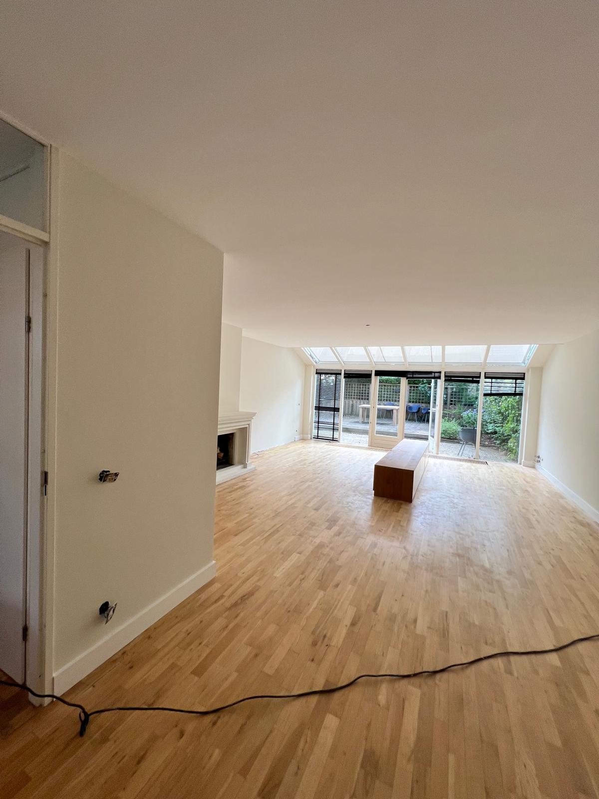 Ruime woonkamer met open haard en tuindeuren