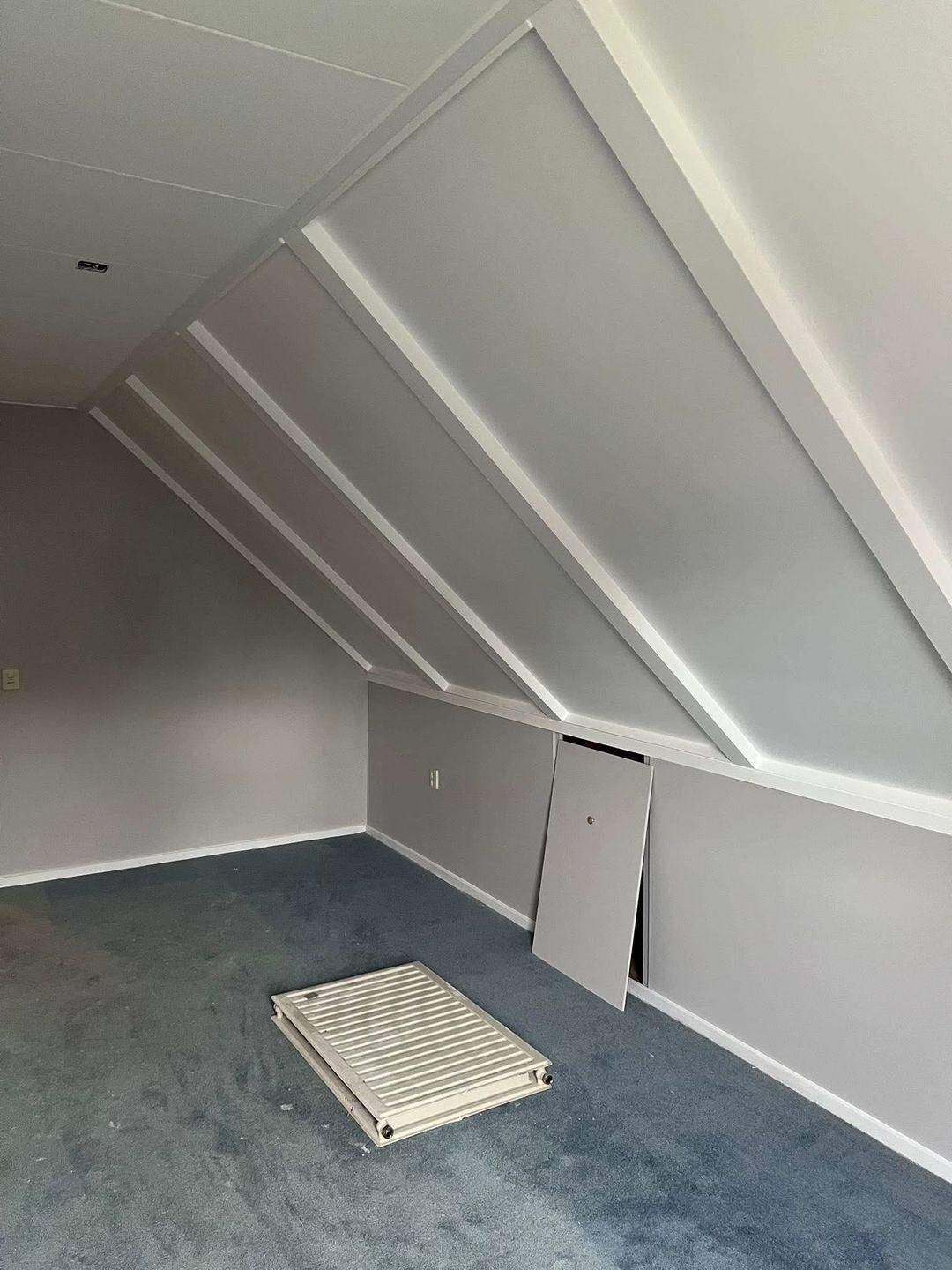 Zolderkamer met afgewerkte wanden, paneeldeuren en blauw tapijt
