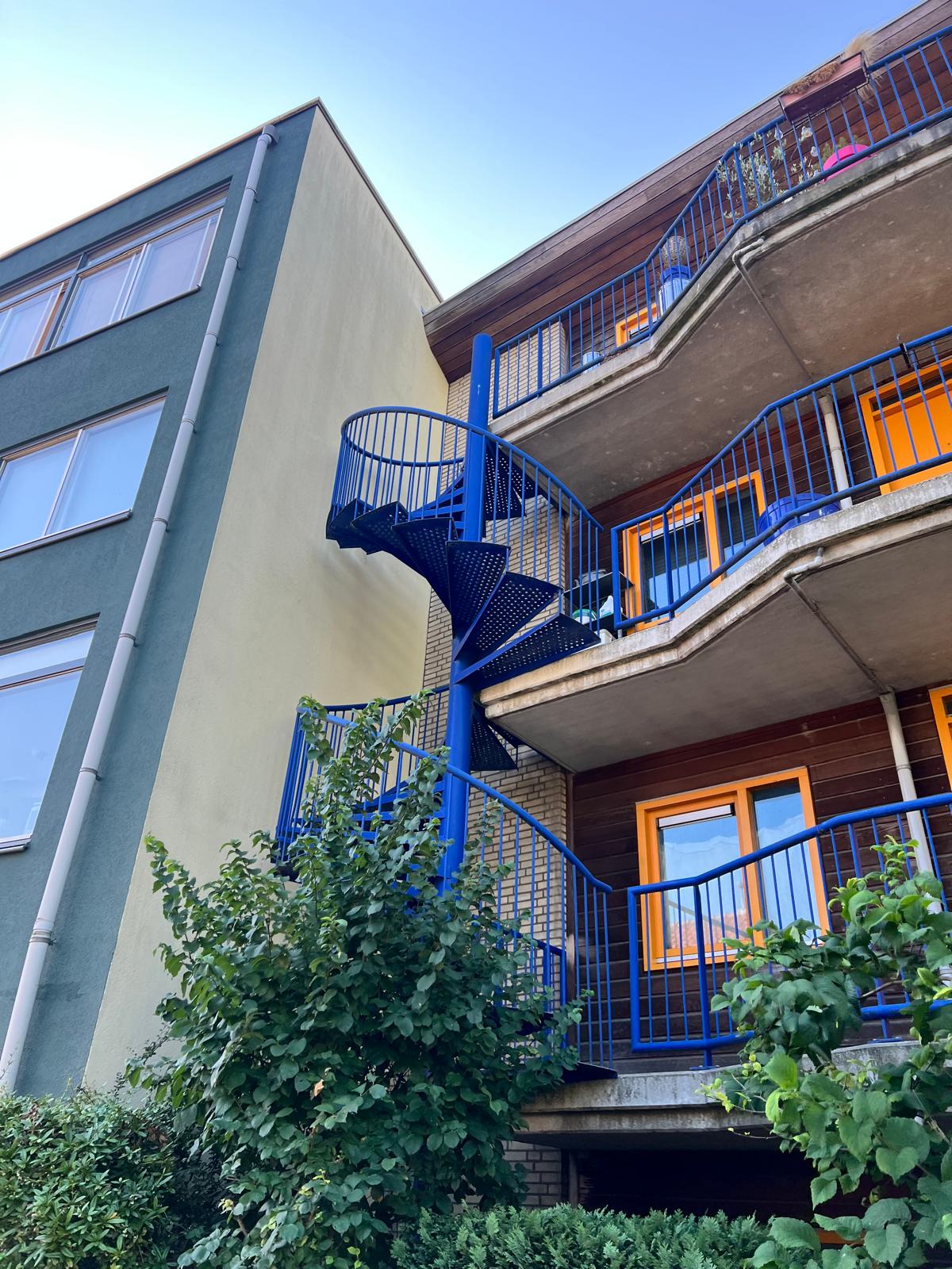 Blauwe spiltrap en geschilderde balkons van het VvE complex