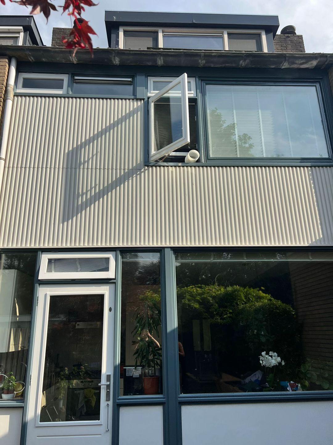 Voorgevel van woning in Delft met open raam en geschilderde kozijnen